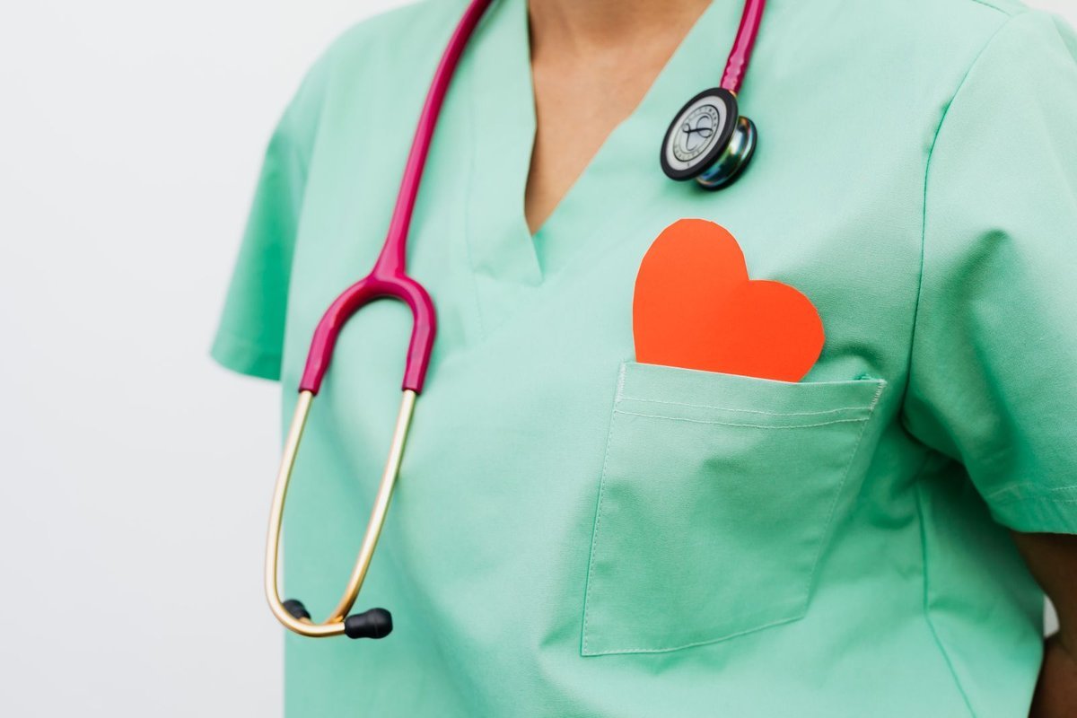 Mint-green scrubs with a pink stethoscope and a red paper heart in the pocket